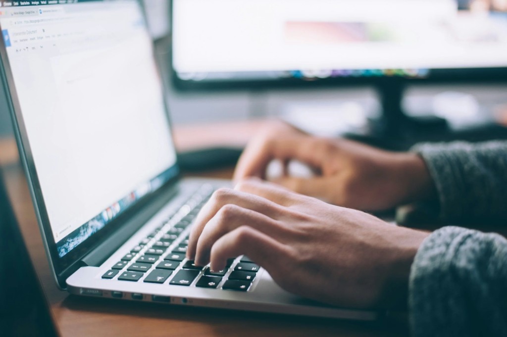 Person holding phone above laptop